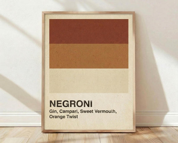 May include: Framed minimalist poster with horizontal color blocks in rust red, warm orange, and cream representing Negroni cocktail ingredients. Bold black text reads "NEGRONI" with ingredients "Gin, Campari, Sweet Vermouth, Orange Twist" below. Light wood frame sits on wooden floor against white textured wall with soft natural lighting and shadows.