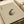 May include: Traditional Japanese ink painting of a spotted frog on beige textured paper, displayed in an open book or portfolio with cream-colored pages and ribbon binding, photographed on a light wooden surface with soft natural lighting