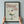 May include: Hands holding a black-framed vintage-style poster featuring red text "Dinner Club" and "The art of indulgence" with an illustration of whipped cream dessert topped with a cherry in a glass coupe, plus "A dash of decadence" text, displayed against a light gray wall in a cream and muted green color palette.