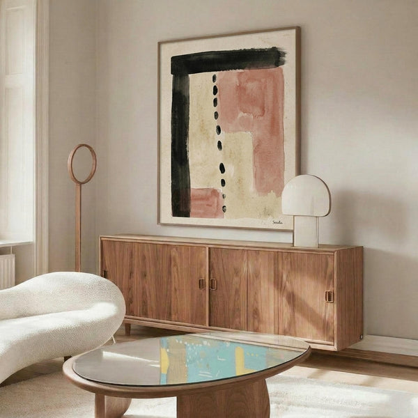May include: Abstract minimalist artwork displayed in modern living room with wooden sideboard and white curved chair. Artwork features black brushstrokes, terracotta pink rectangles, cream sections, and vertical line of black dots on textured white background in thin wooden frame. Room has neutral beige walls, oval glass coffee table, and contemporary furniture styling.