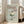 May include: Framed vintage-style poster with pale mint green background displaying red text reading "Dinner Club" and "The art of indulgence" alongside an illustration of a coupe glass filled with white whipped cream topped with a dark cherry. The poster reads "A dash of decadence" at bottom. Light wood frame sits on hardwood floor against white walls near beige upholstered chair and tall windows with natural lighting.