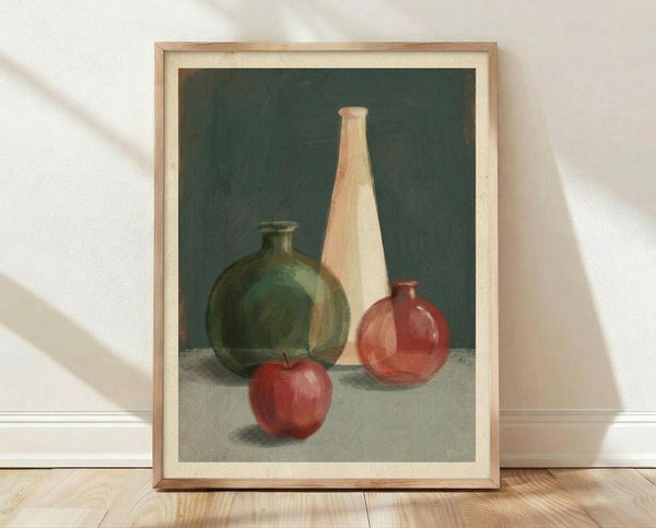 May include: Framed still life painting leaning against white wall on wooden floor. Artwork shows three ceramic vases in green, cream, and terracotta colors alongside a red apple, set against dark green background. Natural wood frame with cream matting. Soft natural lighting creates diagonal shadows across the scene.