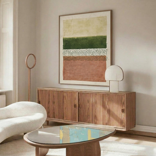 May include: Abstract geometric poster with horizontal bands in sage green, coral pink, white with black dots, displayed in wooden frame above mid-century walnut credenza. Modern living room setting with cream sculptural chair, oval glass coffee table, and minimalist decor on neutral walls.