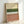 May include: Framed abstract art print leaning against white wall, featuring horizontal bands of watercolor-style colors including cream, olive green, white with black polka dots, peach, and terracotta pink. Natural wood frame with visible texture and weathered appearance on the artwork surface.
