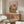 May include: Framed poster with colorful text reading "PASTA DISASTER" showing a tabby cat wearing a chef's hat and golden retriever with sunglasses and apron sitting at a messy table covered in spaghetti, wine bottles, and pasta dishes on pink background. Displayed above mid-century modern walnut credenza next to white curved chair and glass coffee table in bright living room.
