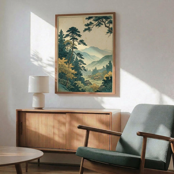 May include: Japanese woodblock print artwork in wooden frame showing mountain landscape with pine trees, traditional buildings, and misty blue-green hills. Displayed above mid-century modern walnut credenza with table lamp. Sage green upholstered armchair with wooden frame in foreground. Warm natural lighting creates shadows on white wall in minimalist living room setting.