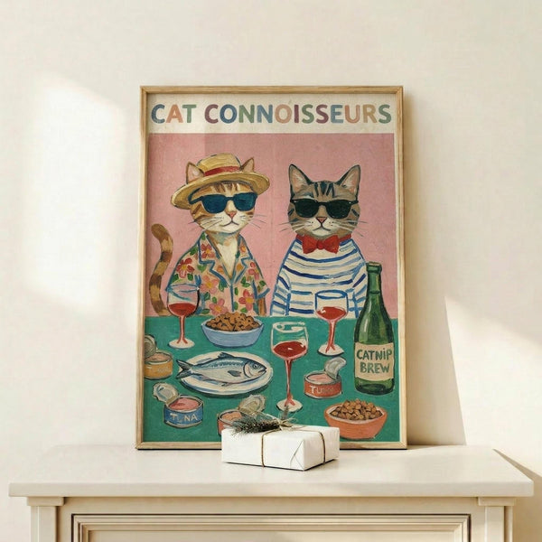 May include: Framed poster showing two anthropomorphic cats wearing sunglasses and stylish outfits sitting at a turquoise table with wine glasses, fish, tuna cans, kibble bowls, and a "Catnip Brew" bottle. The illustration has a pink background with "CAT CONNOISSEURS" text at top in colorful letters. Light wood frame displayed on white wooden shelf with small wrapped gift box beside it.
