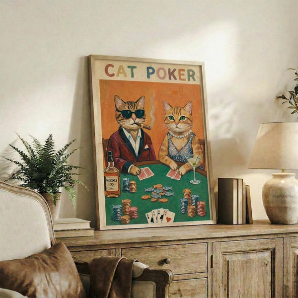 May include: Framed poster showing two cats in vintage style playing poker at green felt table with cards, poker chips, whiskey bottle, and martini glass. Male cat wears sunglasses and burgundy jacket while smoking, female cat wears pearl necklace and blue dress. Orange background with "CAT POKER" text at top in colorful letters. Wood-framed print displayed on rustic wooden sideboard with books, plant, and ceramic vase in warm-lit living room setting.