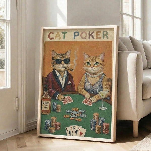 May include: Framed vintage-style poster with "CAT POKER" text showing two anthropomorphic cats at green poker table. Left cat wears sunglasses, burgundy jacket and smokes cigar. Right cat wears pearl necklace, patterned vest and holds martini. Table has poker chips, playing cards showing four aces, whiskey bottle, and fish-shaped snacks. Warm orange background. Light wooden frame leans against beige armchair in bright living room with white walls and windows.