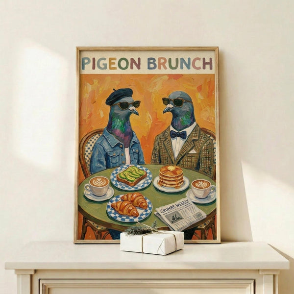 May include: Framed poster showing two anthropomorphic pigeons in human clothing sitting at a green cafe table. The pigeon on left wears a denim jacket and beret, the right one sports a brown tweed suit and bow tie. Both wear sunglasses. Table displays brunch items including avocado toast, croissants, pancakes, and coffee cups with latte art. A newspaper titled "Crumbs Weekly" sits on the table. Warm orange background with painterly brushstrokes. Displayed on white shelf with small wrapped gift