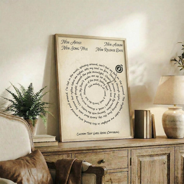 May include: Framed beige poster with elegant typography arranged in spiral text pattern, displayed on rustic wooden sideboard alongside potted fern, ceramic vase, and stacked books. Warm neutral tones with natural lighting in cozy living room setting.