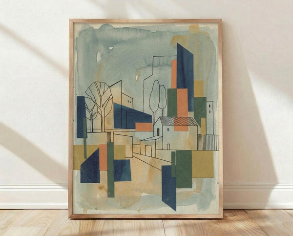 May include: Framed abstract architectural artwork in light wood frame leaning against white wall on wooden floor. Watercolor-style painting features geometric buildings, trees, and urban landscape in muted blues, oranges, greens, and beiges. Modernist cubist composition with overlapping shapes and soft brushwork creates dreamlike cityscape scene.