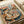 May include: Vintage-style poster print featuring two anthropomorphic cats at a Parisian café table. One orange tabby wears a black beret and patterned scarf, while a brown tabby in striped shirt and glasses reads a philosophy book. Table displays croissants, macarons, coffee, and French press. Eiffel Tower and café awnings visible in background. Artwork shows warm, painted illustration style in cream wooden frame, displayed on white bedding.