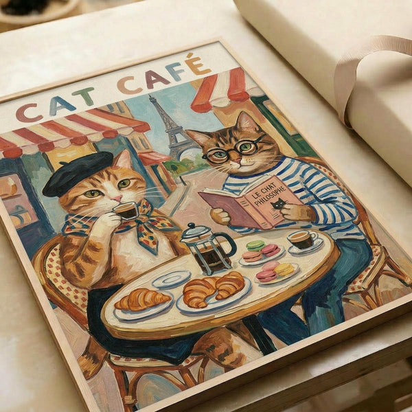 May include: Vintage-style poster print featuring two anthropomorphic cats at a Parisian café table. One orange tabby wears a black beret and patterned scarf, while a brown tabby in striped shirt and glasses reads a philosophy book. Table displays croissants, macarons, coffee, and French press. Eiffel Tower and café awnings visible in background. Artwork shows warm, painted illustration style in cream wooden frame, displayed on white bedding.