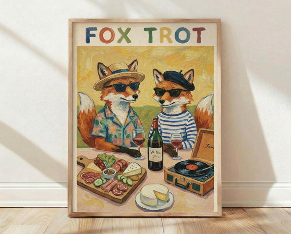 May include: Framed art print leaning against white wall on light wood floor. Features two anthropomorphic foxes in sunglasses sitting at picnic table with wine glasses, charcuterie board, cheese wheel, and vintage record player. One fox wears striped shirt and beret, other in tropical shirt and hat. Colorful hand-lettered "FOX TROT" title above painted scene with warm yellow background and painterly texture.