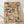 May include: Framed art print leaning against white wall on wooden floor, featuring densely packed colorful book spines arranged in mosaic pattern. Books shown in various sizes with vintage colors including deep blues, warm oranges, reds, creams, and greens. Natural wood frame surrounds the artwork. Soft natural lighting creates gentle shadows on textured white wall.