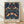 May include: Framed poster print featuring William Morris's ornate Victorian pattern with symmetrical design of birds, strawberry plants, and flowers in rich blues, greens, and coral tones on dark navy background. Light wood frame leans against white wall on light wooden floor with soft natural lighting creating gentle shadows.