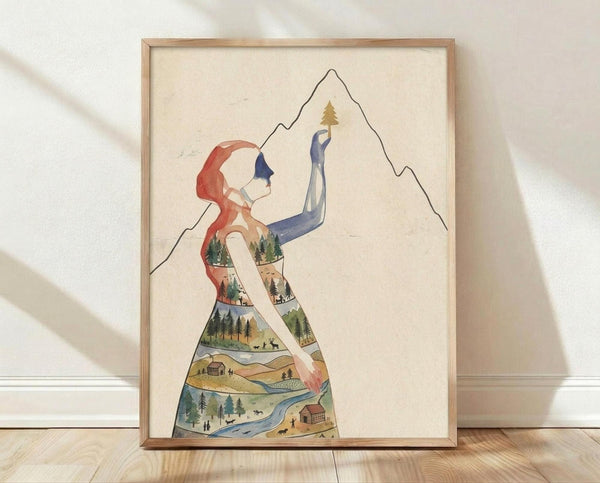 May include: Framed art print leaning against white wall on light wood floor. Artwork shows stylized woman silhouette filled with layered landscape scenes including forests, mountains, rivers, and small cabins in earthy greens, blues, and browns. Woman has flowing red hair and reaches toward mountain outline with small golden tree. Natural wood frame, cream background, soft natural lighting creates shadows on textured white wall.