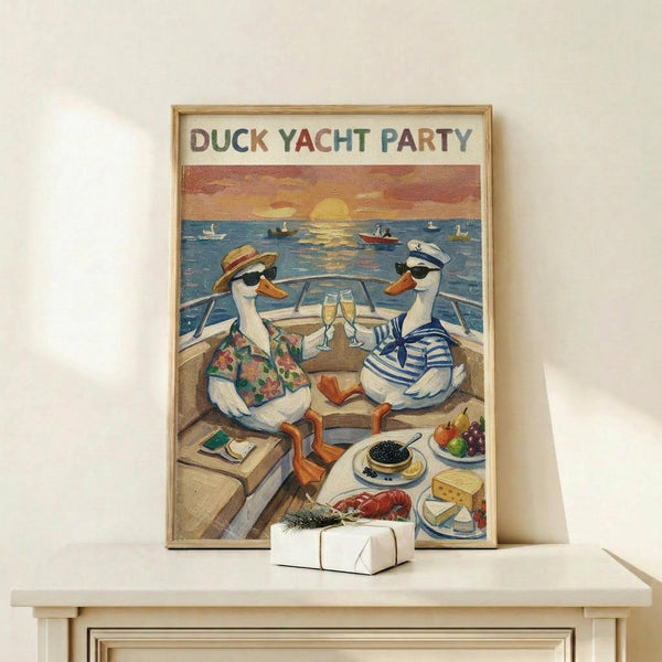 May include: Framed poster showing two ducks in sunglasses relaxing on a yacht deck at sunset, one wearing a Hawaiian shirt and sun hat, the other in a striped nautical shirt and captain's cap. They're toasting with champagne glasses while enjoying gourmet food including caviar, lobster, and cheese. The scene features a golden sunset over water with boats in the background. The artwork has a vintage illustration style with warm colors. A small wrapped gift sits on the light wood shelf below the