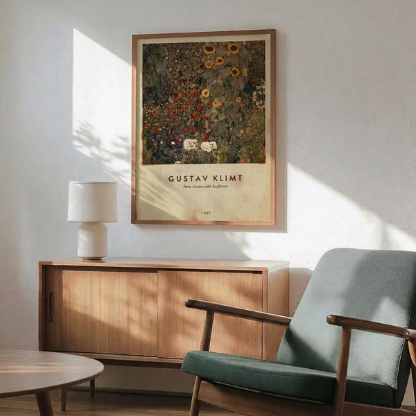 May include: Framed Gustav Klimt poster featuring a lush garden scene with vibrant sunflowers, red poppies, and dense wildflowers in rich greens and earth tones, displayed above a mid-century modern wooden sideboard. Light green upholstered armchair with wooden frame sits nearby, alongside a white ceramic table lamp and small round coffee table, all bathed in natural window light creating geometric shadows on white walls.