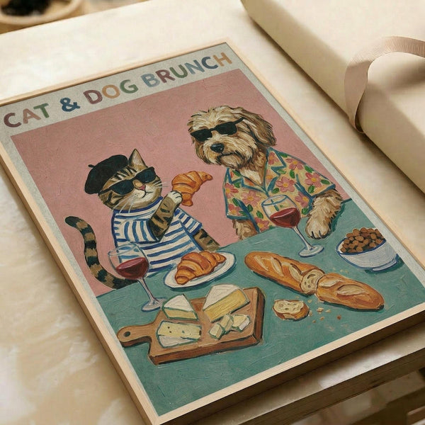 Vintage-style poster print featuring a tabby cat in sunglasses and striped shirt holding a croissant, sitting at a brunch table with a scruffy dog wearing sunglasses and tropical shirt holding wine. Table displays croissants, cheese board, baguette, wine glasses, and dog kibble on teal surface against pink background. Print shown flat on white paper with ribbon nearby.
