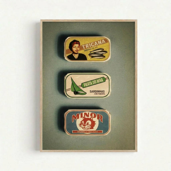 Three vintage Portuguese sardine tin labels displayed in a wooden shadow box frame against olive green fabric backing. The top label shows "Tricana" with a woman's portrait and sardines, the middle shows "Prata Do Mar" with a green sailboat and "Sardinhas com Pimento" text, and the bottom displays "Minor" with a red cat mascot logo. Each tin label features retro typography and colorful illustrations in yellow, cream, green, and red tones.