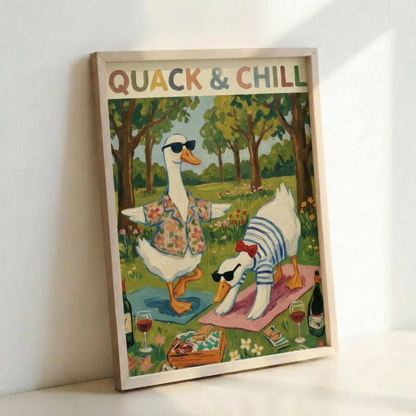 May include: Framed poster print leaning against white wall showing two white ducks relaxing in a sunny park setting. One duck wears sunglasses and floral shirt sitting in orange chair, the other in striped shirt lies on pink yoga mat. Wine glasses, books, and picnic items scattered on grass around them. Colorful lettering at top, natural wood frame, cottage core illustration style.