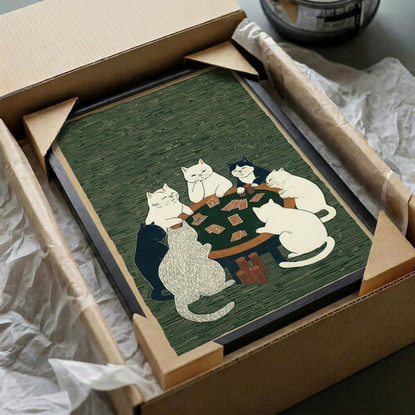 May include: Framed artwork featuring six cats in various colors (white, black, striped) sitting around a dark wooden table playing cards, rendered in Japanese woodblock print style with green textured background. The piece is being unpacked from a cardboard shipping box with protective wrapping, showing the wooden frame and matting details.