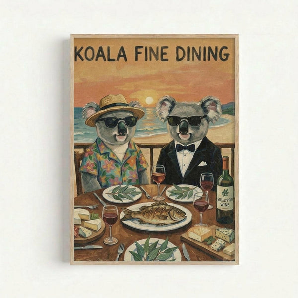 Framed vintage-style poster featuring two koalas in sunglasses dining at a waterfront restaurant. One koala wears a straw hat and tropical shirt, the other a black tuxedo with bow tie. The wooden table displays eucalyptus leaves on plates, grilled fish, cheese, wine glasses, and a bottle labeled "Eucalyptus Wine." Behind them, an ocean sunset creates a warm orange and yellow sky. The poster has a light wooden frame and warm, nostalgic color palette.
