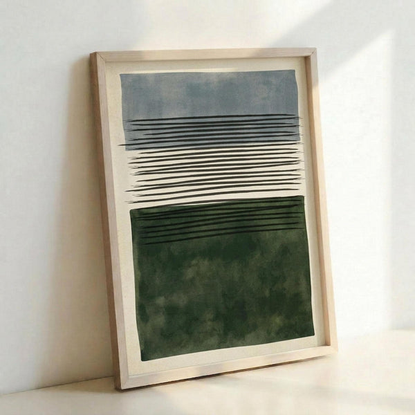 A framed abstract artwork featuring horizontal bands of color and linear elements. The top section shows gray-blue watercolor washes with black horizontal lines, transitioning through a white middle section with dense black linear marks, and ending in a deep forest green watercolor section at the bottom. The piece is displayed in a light wood frame, leaning against a white wall corner, creating subtle shadows.