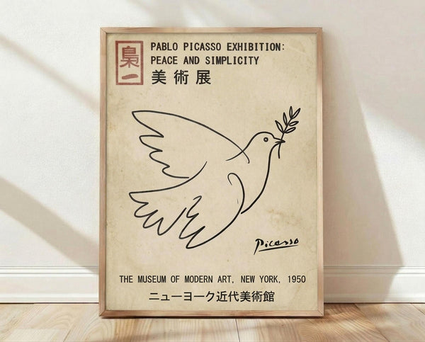 May include: Framed vintage-style exhibition poster featuring Picasso's iconic line drawing of a dove carrying an olive branch, displayed against white fabric backdrop on wooden floor. Cream-colored aged paper background with black line art, red square logo, English and Japanese text including "The Museum of Modern Art, New York, 1950." Natural wood frame with subtle grain texture.