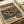 Retro-style poster featuring a vintage turntable and cassette tape with headphones in muted green, orange and cream colors. Japanese text appears at top and bottom of the design. The poster lies flat on white paper with a partial view of what appears to be a tape dispenser in the corner, photographed from above in soft natural lighting.