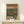May include: Vintage-style Japanese poster with turntable and cassette player illustration in green and orange colors, displayed in wooden frame on white wooden shelf next to small wrapped gift with evergreen sprig. Retro advertisement design features bold Japanese text and audio equipment drawings in weathered, distressed style against muted background.