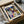 May include: Framed Paul Klee abstract geometric artwork displayed in cardboard shipping box with protective tissue paper and wooden frame pieces. The colorful modernist print features overlapping triangles, rectangles and circles in blues, yellows, greens, oranges and earth tones creating a complex geometric composition. Black frame surrounds cream-colored poster with Bauhaus Archiv and exhibition text visible at bottom.