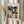 May include: Person in beige ruffled sleeves holding framed poster featuring Paul Klee's abstract geometric artwork in vibrant blues, greens, oranges, and earth tones. Light wood frame against white curtained window with dried pampas grass visible on left side.