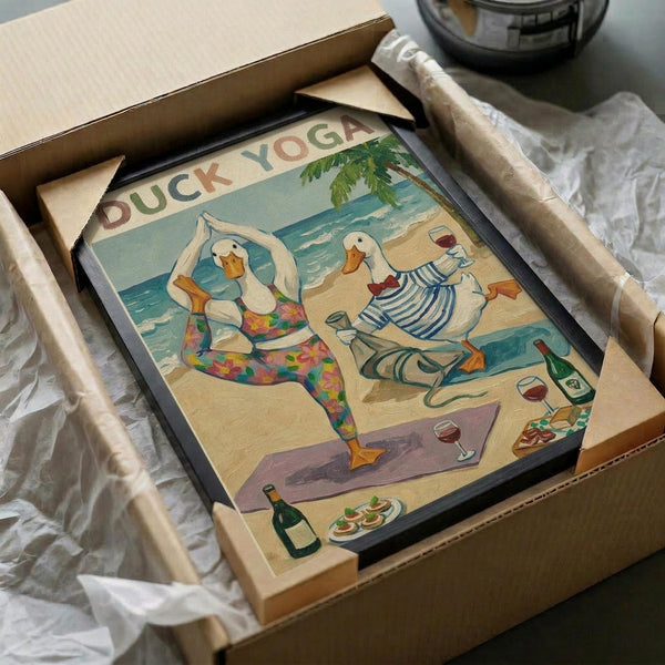 May include: Framed poster print in black frame showing three white ducks doing yoga poses on a tropical beach. One duck wears colorful floral leggings in tree pose, another in striped outfit doing warrior pose, third holds wine glass. Palm tree, ocean waves, wine bottles and appetizers scattered on sand. Vintage-style illustration with "DUCK YOGA" text at top. Print packaged in cardboard box with protective wrapping on white surface.