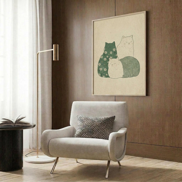 May include: Three stylized cats artwork in cream-colored frame mounted on wood paneled wall above beige upholstered armchair. One green cat with white daisy pattern, one outlined white cat, one smaller cream cat, and one green textured cat grouped together. Modern reading nook with gold floor lamp, geometric throw pillow, and dark round side table with open book.