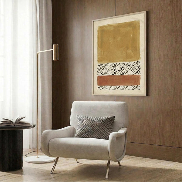 May include: Modern abstract wall art print in warm terracotta, ochre yellow, and cream with dotted patterns, displayed in a contemporary living room setting with beige upholstered armchair, gold floor lamp, and wood-paneled walls
