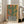 May include: A framed poster print featuring a green saguaro cactus in a black and white striped pot against a warm orange and yellow background. The artwork has a vintage, textured appearance and is displayed in a light wood frame leaning against a white wall next to a beige sectional sofa in a bright, modern living room with large windows.