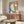 May include: Abstract artwork in warm wood frame hanging above mid-century walnut credenza in modern living room. Art features organic curved shapes in terracotta, sage green, and navy blue with textured brushstrokes and cream moon against earth-toned background. White sculptural chair and oval glass coffee table complete the scene.