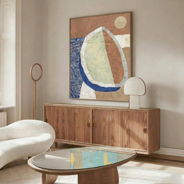 May include: Abstract artwork in warm wood frame hanging above mid-century walnut credenza in modern living room. Art features organic curved shapes in terracotta, sage green, and navy blue with textured brushstrokes and cream moon against earth-toned background. White sculptural chair and oval glass coffee table complete the scene.