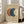 May include: Abstract art print in light wood frame leaning against white wall next to beige sofa. Artwork features three overlapping circles in rust orange, navy blue, and cream on textured beige background. Modern minimalist living room setting with natural light from windows, clean white walls and neutral furniture.