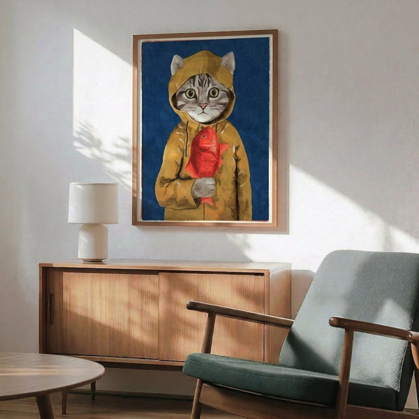 May include: Framed artwork showing a tabby cat wearing a yellow raincoat and holding a red fish, displayed on white wall above wooden sideboard with table lamp. Mid-century modern living room setting with teal upholstered chair, round coffee table, and natural sunlight creating shadows on wall.