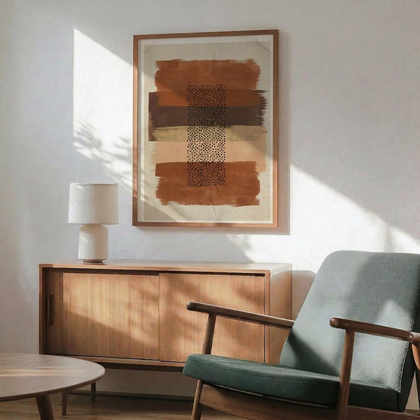 May include: Abstract art print with horizontal brushstrokes in terracotta, ochre, and cream tones with a central dotted pattern, displayed in a wood frame above a mid-century modern credenza. Scene shows mint green upholstered chair with wooden arms, ceramic table lamp, and dramatic window shadows on white wall.
