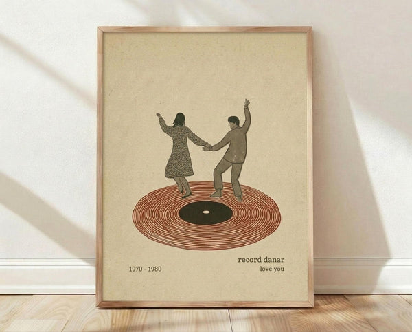 May include: Framed vintage-style poster with cream background showing two silhouetted figures dancing on a vinyl record. The woman wears a patterned dress, the man is in solid clothing, both with arms raised while holding hands. The record is rendered in reddish-brown with black center label. Text below reads "record danar 1970-1980 love you" in small brown letters. Natural wood frame sits on light wooden floor against white wall with soft shadows.