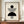 May include: Framed Bauhaus-style poster with geometric black and white design featuring circles and semicircles with concentric line patterns, displayed on wooden sideboard next to white ceramic vase and stacked books against cream paneled wall in modern interior setting.