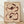 May include: Framed abstract floral artwork leaning against white textured wall on light wood floor. Two stylized poppy flowers painted in warm brown and peachy pink tones on cream background. Loose, painterly brushstrokes create organic petal shapes with dark centers and thin stems. Natural wood frame surrounds the botanical illustration in minimalist room setting with soft natural lighting.