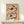 May include: framed abstract floral artwork displayed on light wood shelf against white wall. Two large stylized poppy blooms rendered in earthy brown and burgundy brushstrokes with cream petals and dark centers on beige background. Natural wood frame complements minimal styling with small white wrapped gift beside artwork.