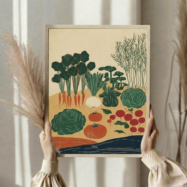 May include: Person in cream ruffled sleeves holding framed botanical print featuring various vegetables including leafy greens with orange roots, red tomatoes, cabbages, and radishes in vintage illustration style with green, orange and navy colors. Dried pampas grass visible beside figure against soft neutral curtained background.
