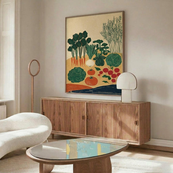 May include: Framed vegetable garden harvest illustration print displayed above a walnut credenza in a modern living room. The artwork features colorful vegetables including carrots, tomatoes, cabbage, and leafy greens on a cream background with thin wood frame. Room shows white curved chair, oval glass coffee table, floor lamp, and neutral decor styling.